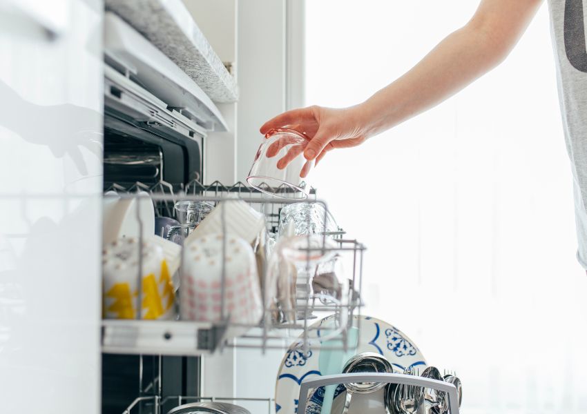 person-filling-dishwasher-with-glass